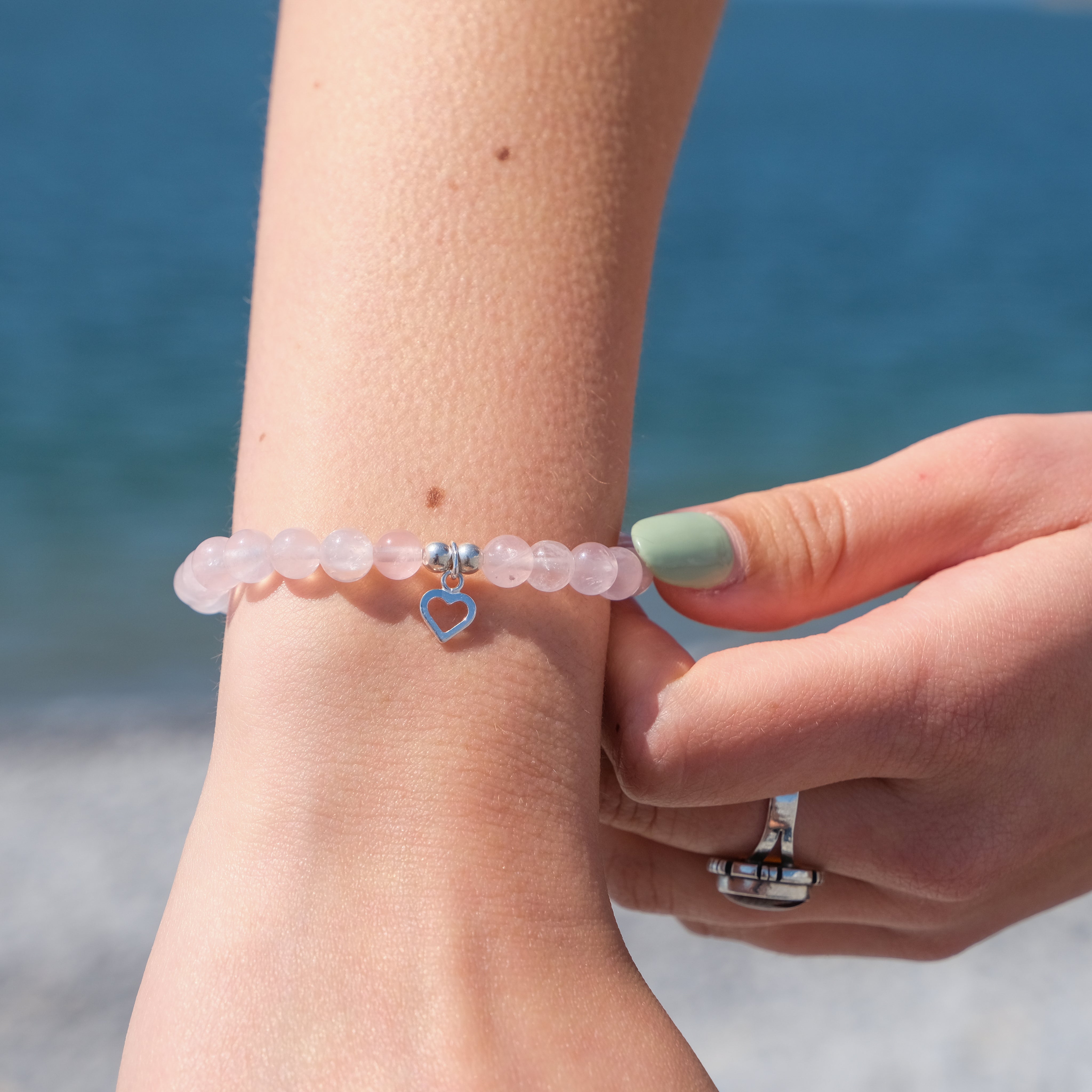 A model wearing A rose quartz crystal bracelet with silver love heart charm