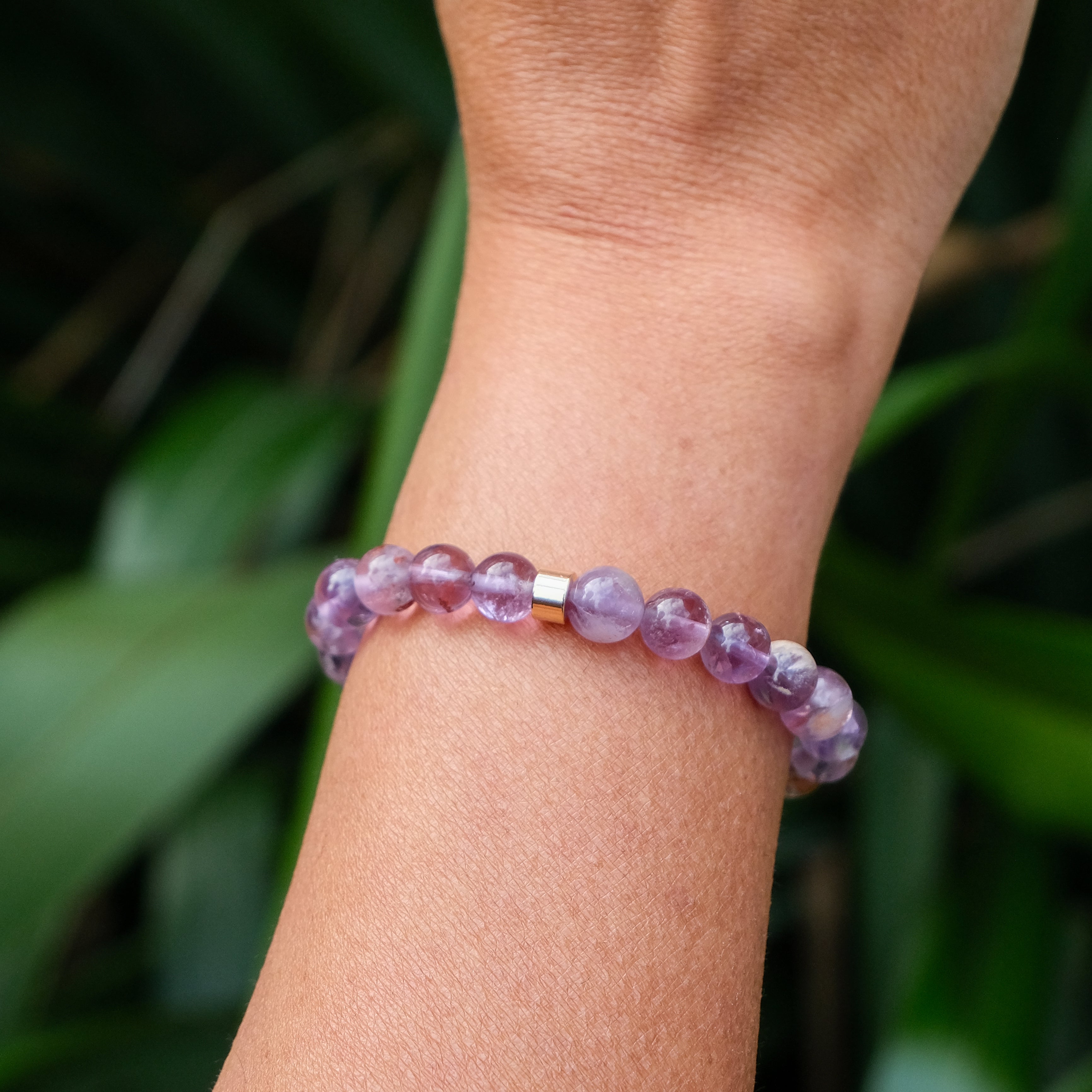 The back of a phantom amethyst bracelet with gold accessory worn on a model's wrist