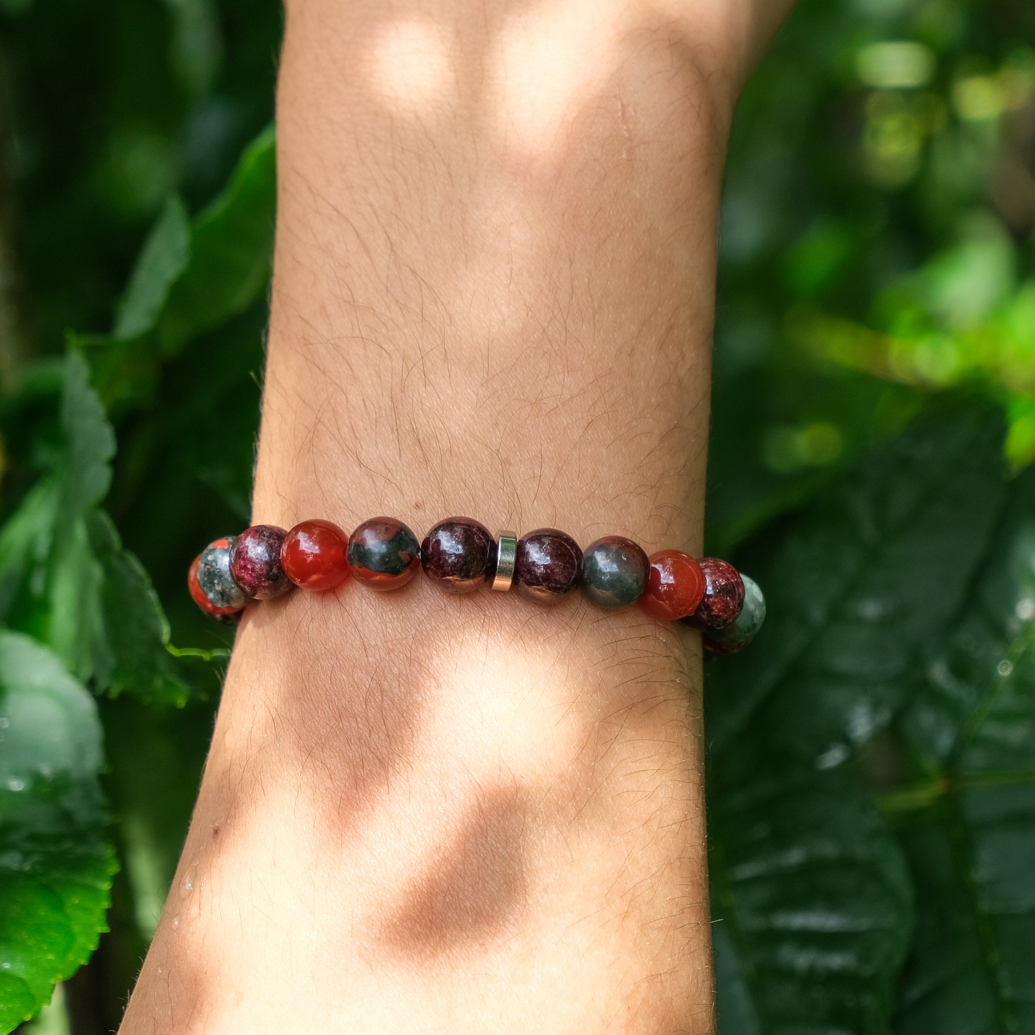 A model wearing an 8mm garnet, carnelian and bloodstone gemstone bracelet with stainless steel accessories