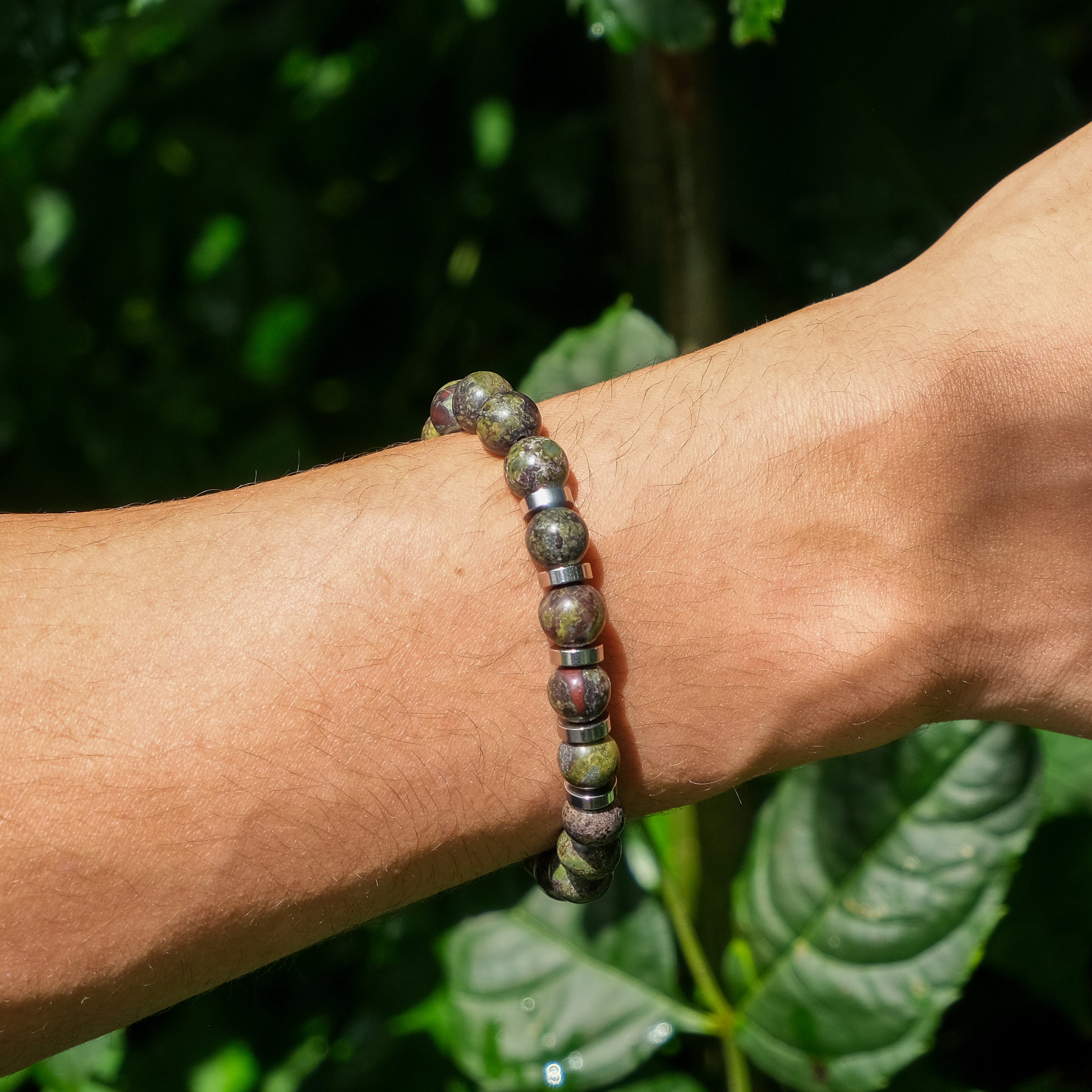 A model wearing a 8mm dragon's blood jasper gemstone bracelet with stainless steel accessories