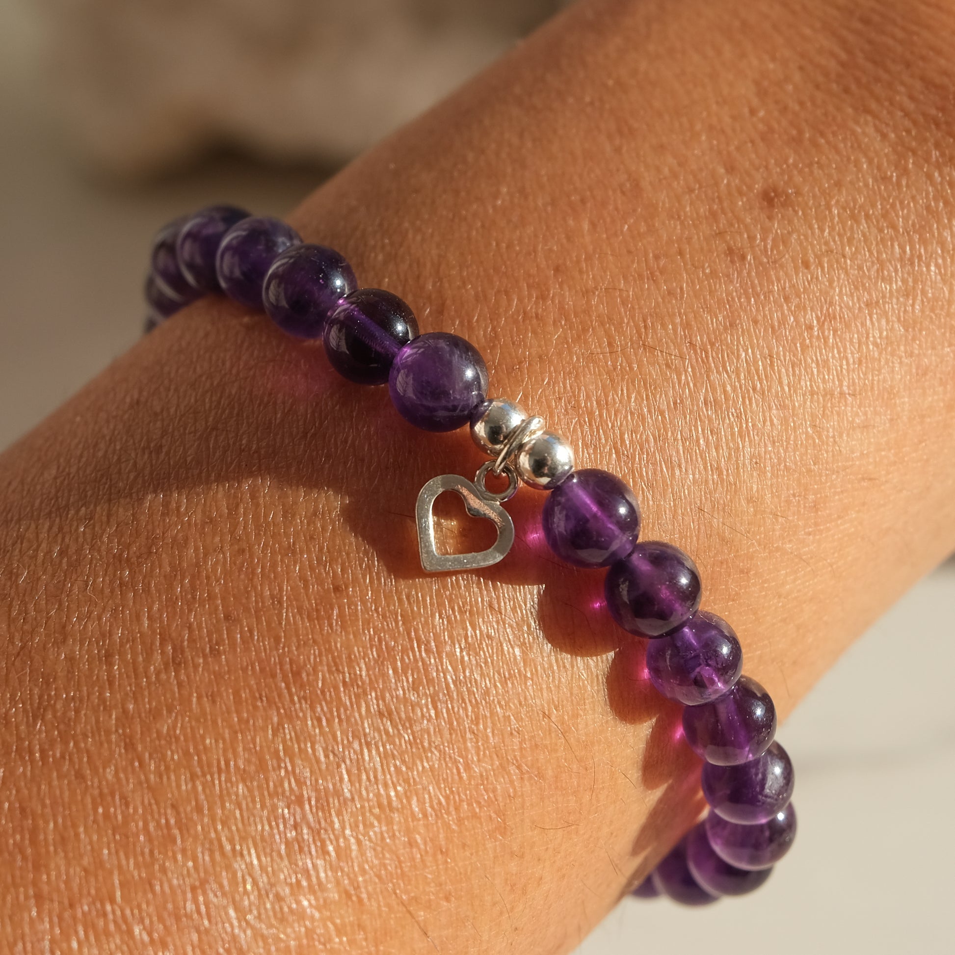 Amethyst gemstone bracelet in 6mm with gold heart charm worn by a model.