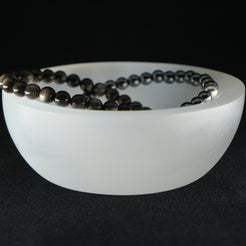 A selenite crystal charging bowl with crystal bracelets inside